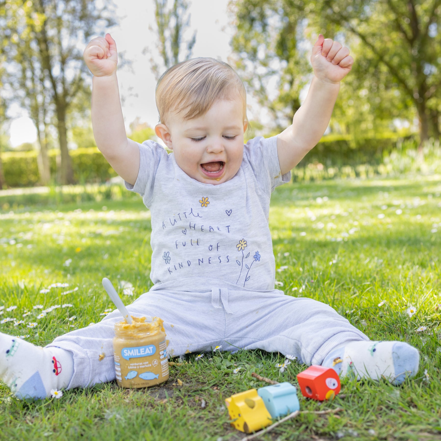 Niño en parque comiendo tarrito ecológico de verduras y pescado