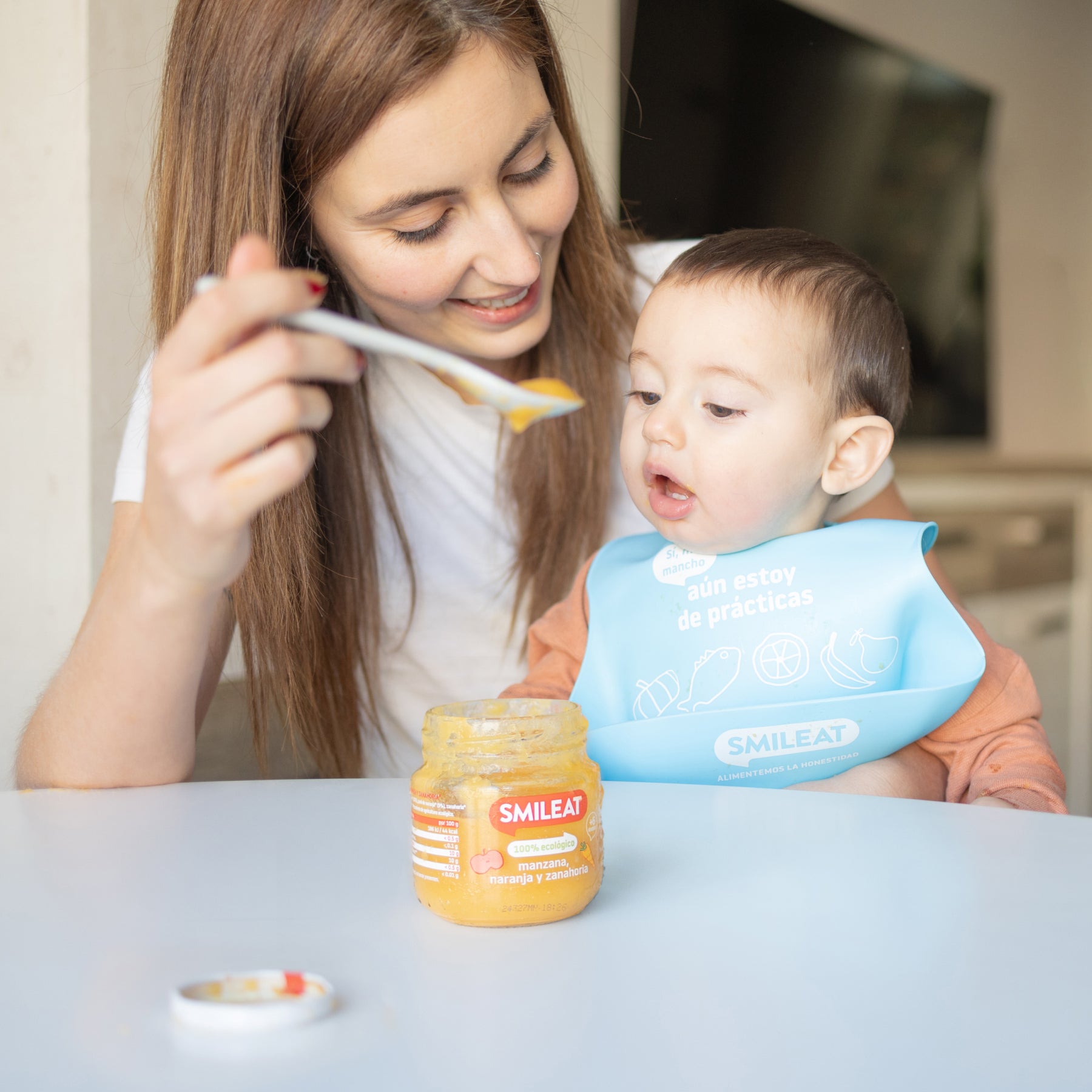 Madre alimentando a niño con tarrito ecológico de frutas