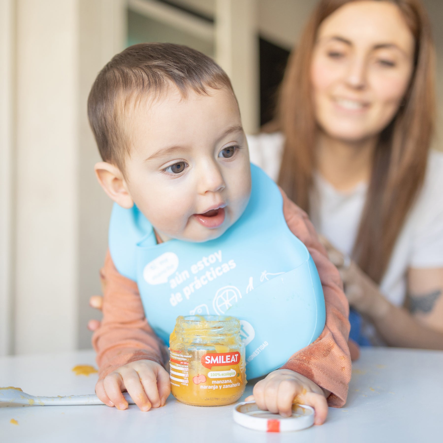 Niño con madre comiendo tarrito ecológico de manzana, naranja y zanahoria