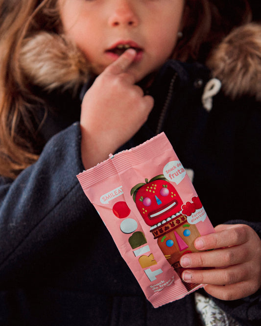 Niña comiendo snacks de fruta sin azúcar añadido con formas divertidas