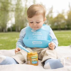 Niño con babero y tarrito ecológico de arroz, pavo y verduras