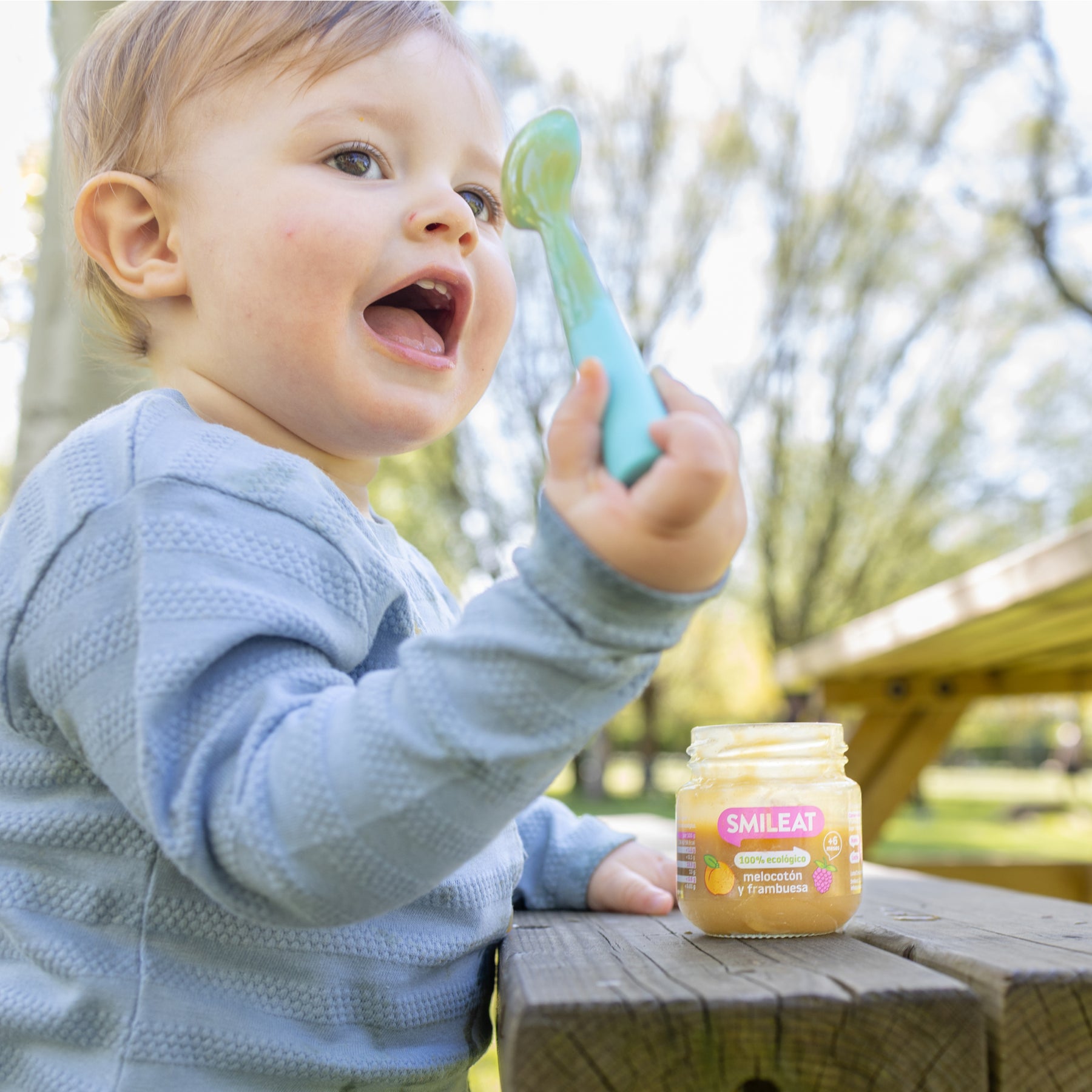Niño comiendo tarrito ecológico de melocotón y frambuesa