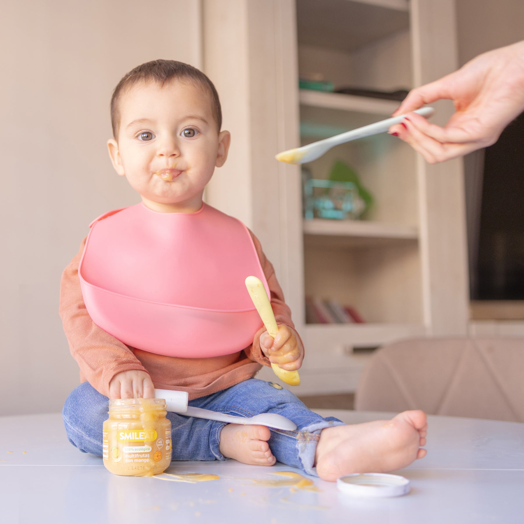 Niño con babero comiendo tarrito ecológico multifrutas