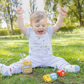 Niño en parque comiendo tarrito ecológico de verduras y pescado