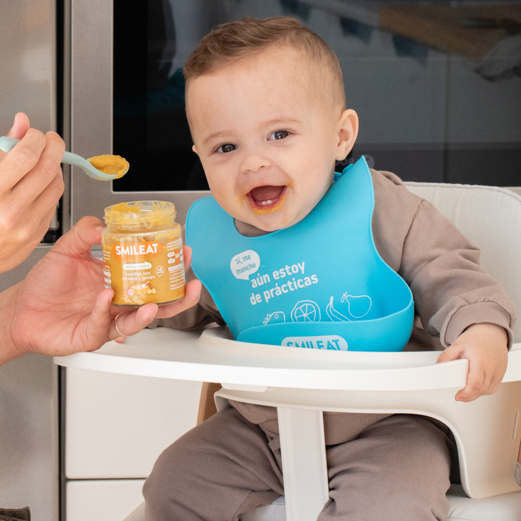 baby eating a small jar of cocidito with ham and veal